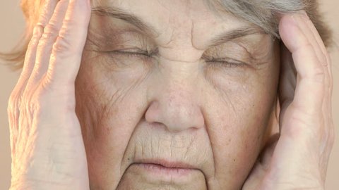 The old woman suffers from headaches. Face close up