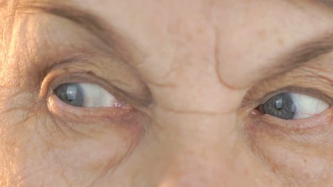 Old woman looks through the eyes in different directions. Close up