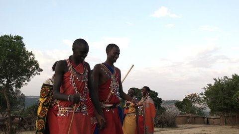 low angle shot of a group of maasai women and men from a village near maasai mara dancing in pairs