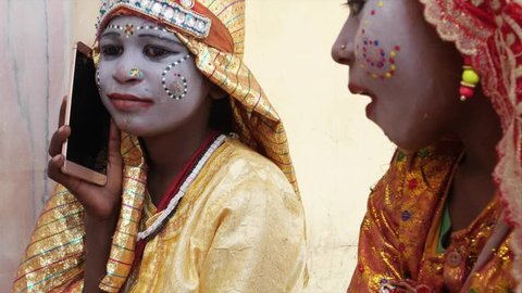 Young Girls on cell phone mobile dressed as Hindu goddess with make-up and traditional clothing at the Pushkar Mela festival in Rajasthan, India 