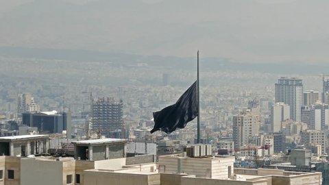 Black flag the symbol of Islam waving in wind over buildings of a big city