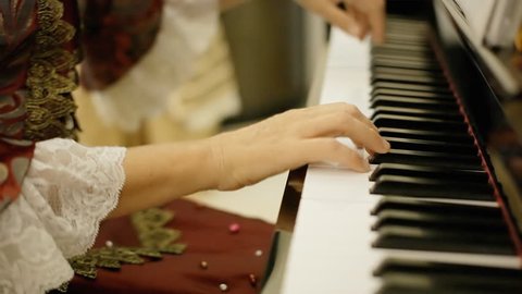 A female pianist, wearing clothes of the 18th century nobility, playing a rondo by Wolfgang Amadeus Mozart on a piano.
