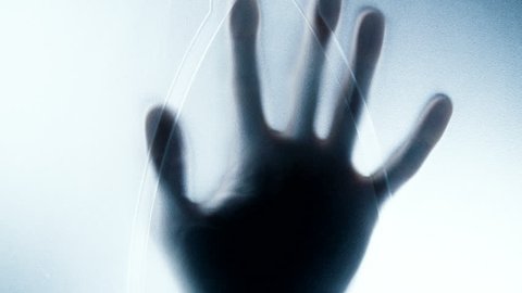 Horror movie scene: hand silhouette behind the window. Hand hits the matte glass surface and slowly sinking on the way down. UHD video 3840x2160.