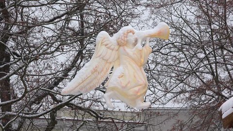 Angel statue silhouette hanging in heavy snow blizzard in christmas town