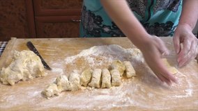 A woman kneads dough on a wooden cutting board  