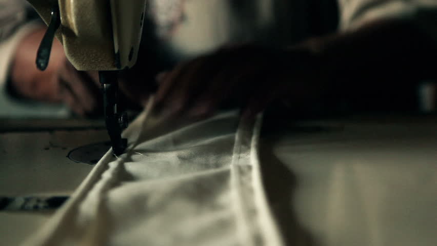 Close up of male hands tailoring on a vintage sewing machine.