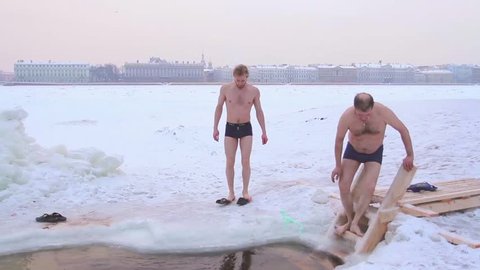 ST. PETERSBURG, RUSSIA - December 2, 2015:Man is immersed in cold water, down the stairs in cold water in ice hole at winter. Then be baptized, and dives into the water. 