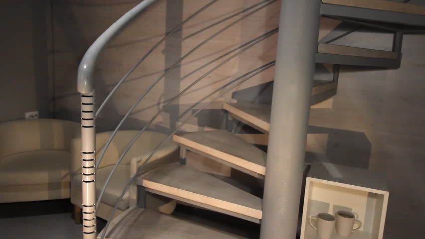 Couple without shoes going upstairs in their home. Woman is pulling her boyfriend to follow her upstairs. Spiral staircase in the apartments
