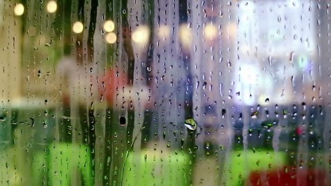 Water drops sliding down on store window glass and blurred interior view