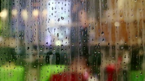 Water drops sliding down on store window glass and blurred interior view