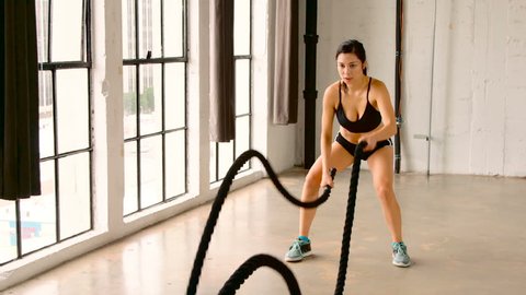 Athletic Female Working Out Using Battle Ropes. Crossfit. Slow Motion.