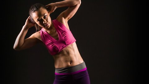 Athletic Asian woman working out in front of a black background.