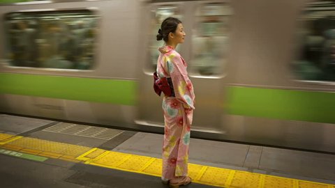 Attractive Japanese woman in a kimono waiting for her train. Tokyo Japan.