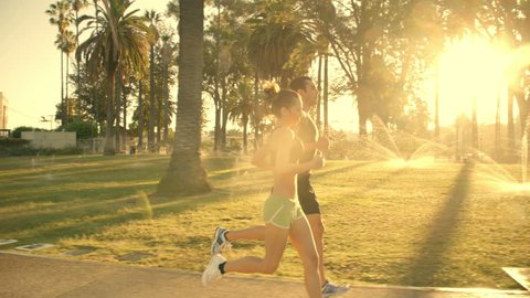 Athletic Couple Jogging through a park. Slow Motion.