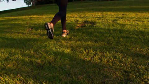 Athletic Woman Working Out. Running up a grass covered hill. Slow Motion.