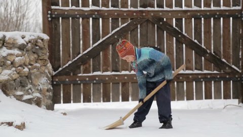Boy removes snow shovel near the house. Cleaning snow in the winter near the house. The child cleans shovel the snow covered track.  