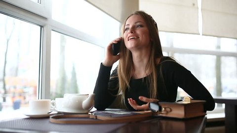 The woman emotionally speaks by phone in a cafe