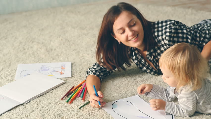 Baby girl draws a picture with pencils. Mother hugs and kisses her. Royalty-Free Stock Footage #22181782