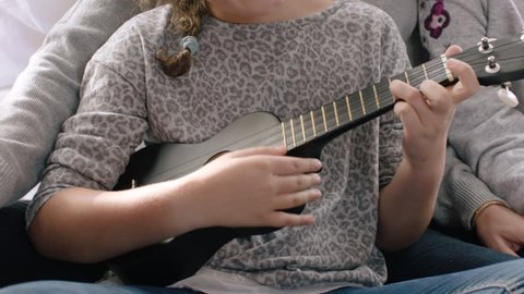Girl playing ukulele and singing with family