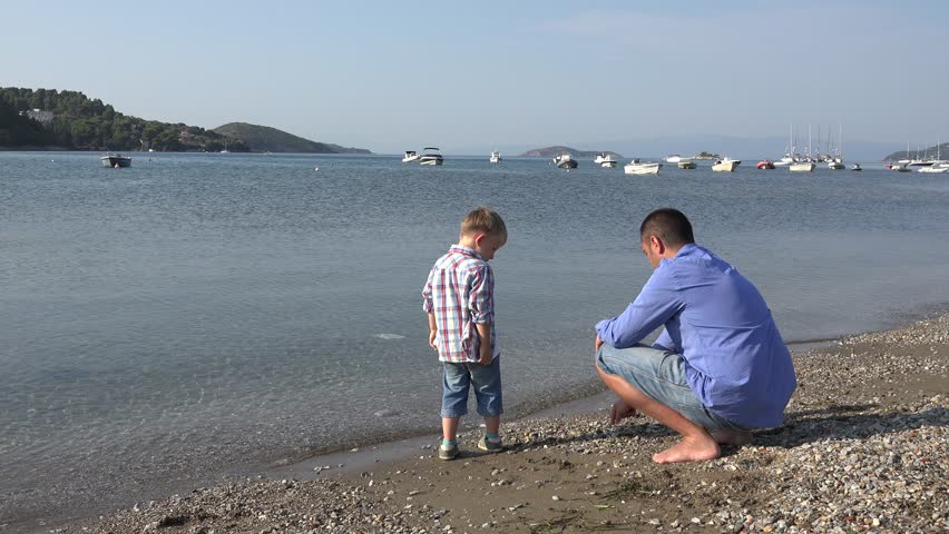 Young father and blond hair son have fun together on seashore, throwing with peddles