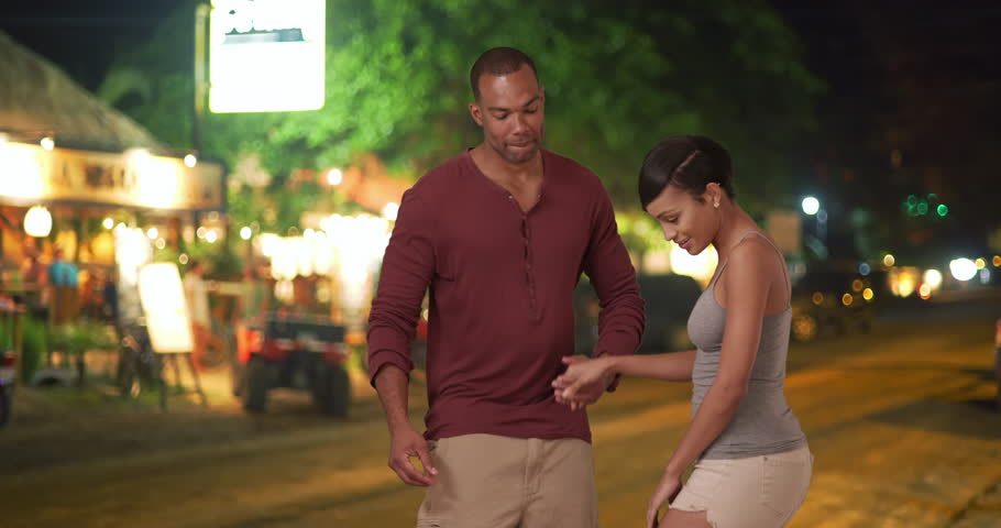 An African American couple dance in a tropical town. A black man and woman have fun doing the tango on their vacation. 4k