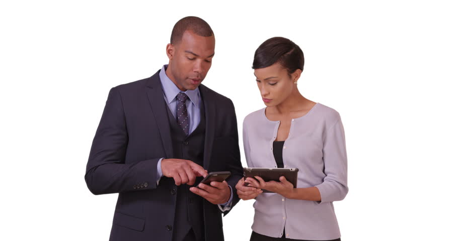 Two black corporate professionals work on their tablet and mobile phone on a white background. Two African American executives plan on their pad and smart phone on a blank backdrop. 4k