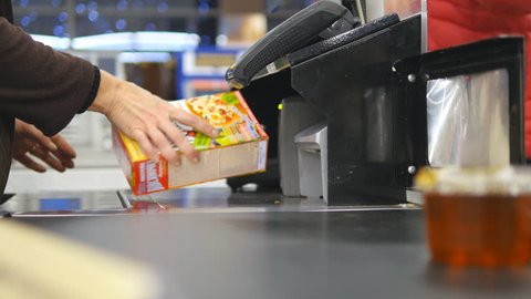 Shopper paying for products at checkout. Foods on conveyor belt at the supermarket. Cash desk with cashier and terminal in hypermarket. Working of cashier. Shopping at store. Close up