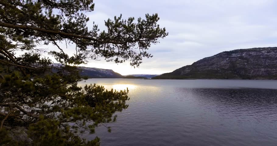 Landscape view over big lake and trees with mountains around,sunshine from the sky / Beautiful landscape with trees and lake in sunshine      	
