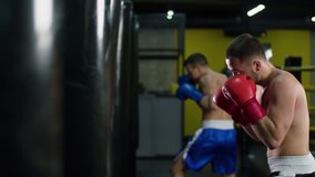 Boxer training punching bag HD slow motion video. Fighter blows hook jab punch, working hands with boxing gloves  