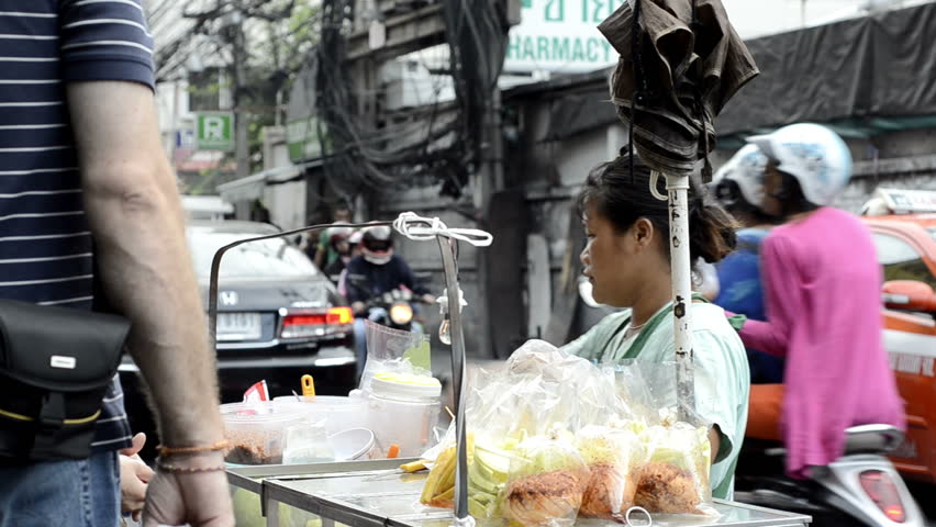BANGKOK - CIRCA MAY 2012: A woman cutting up and bagging fruit from her vendor