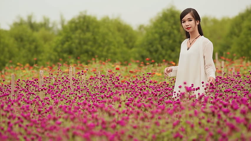 Vietnamese girl with long black hair standing in a plantation purple flowers.