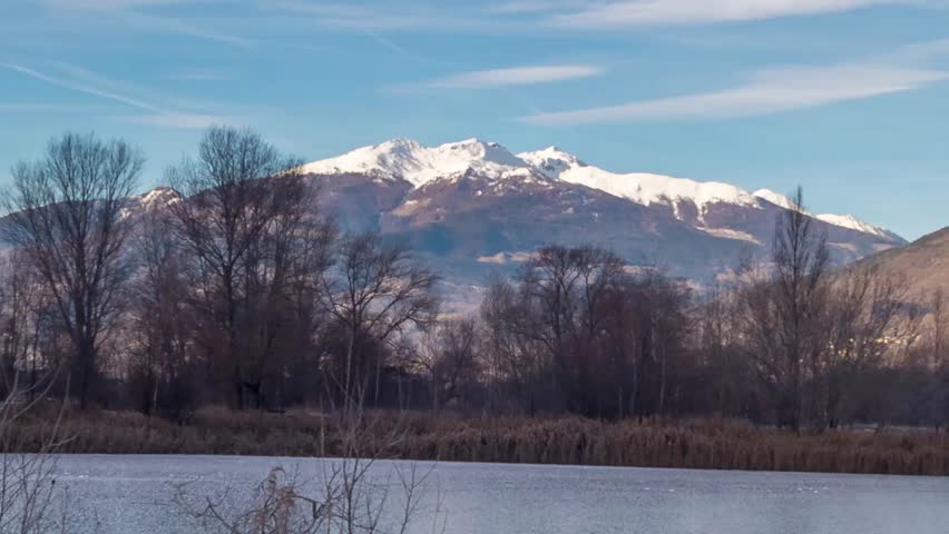 park with a frozen lake in the winter and mountains background, timelapse, hyperlapse video