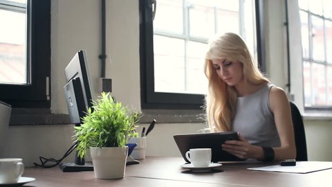 Young businesswoman working on tablet computer in office, dolly shot
