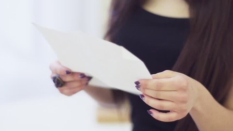Portrait of stylish young woman with brown hairs reading letter in apartment