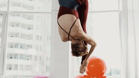 Attractive thoughtful mature woman doing poses of aerial yoga using hammock
