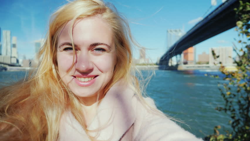 Young tourist in a pink coat takes himself on the video, holding the camera in his hands. Against the backdrop of the skyscrapers of Manhattan