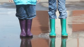 Kids in rain boots jumping chaotically in puddle