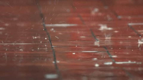 raindrops falling on red floor view from ground level heavy rain with water stream and bubbles, Dark colors darknes