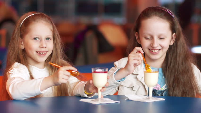 Two sisters eat ice cream at a cafe