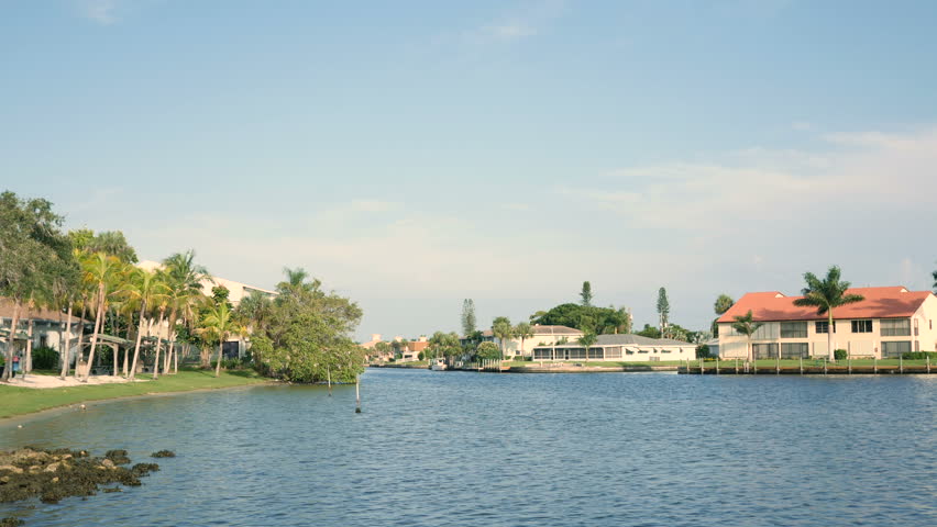 Coastal homes and small tied boats, luxury waterfront real estate in Florida, USA on a sunny day with blue sky.