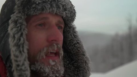 man hands warm in the cold, with a beard in the snow