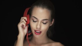 Smiling young woman with red lipstick listening to music on bluetooth headphones and dancing