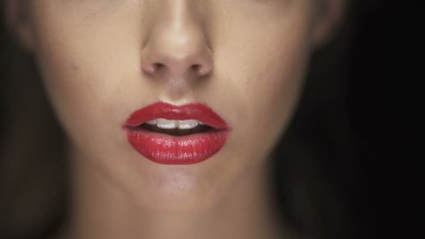 Young woman with red lipstick biting dark chocolate