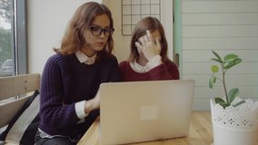 Two girls talking to friends via webchat or having a video chat in cafe 4K
