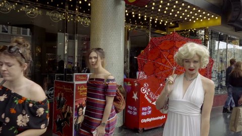 LOS ANGELES - NOV 1, 2016: Marilyn Monroe Impersonator White Dress Red Umbrella Blowing Kiss And Posing For Camera Hollywood Blvd Los Angeles CA. Actors can be seen impersonating icons on the Blvd.