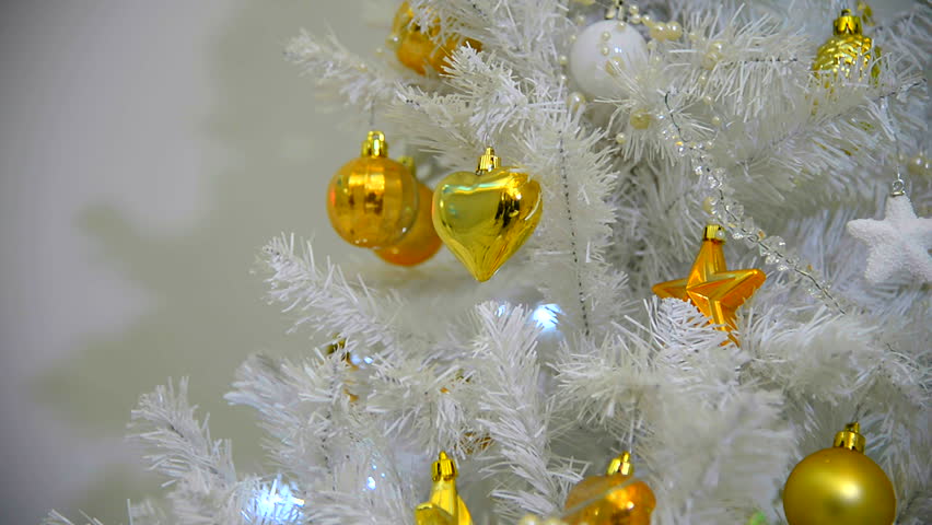 Background with golden balls and cones on the Christmas tree.  White fir tree with flashing lights garlands. New Year Holiday. Artificial decorated Christmas tree with toys. 