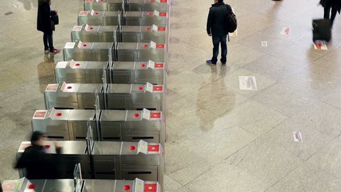 people in underground subway going through turnstile timelapse from above