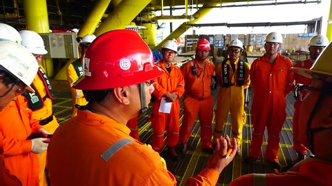 KELANTAN, MALAYSIA - JAN 05 2016 : Unidentified Korean and local offshore workers complete with Personal Protective Equipment (PPE) standing together to listen safety briefing prior to start work.