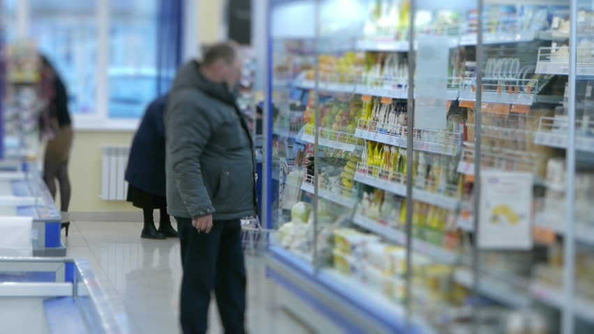 a man chooses food on the supermarket shelf, blurred