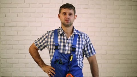 Plumber with an adjustable wrench. A man holds the key plumbing. Worker, builder, repairman, plumber on the brick wall background. 